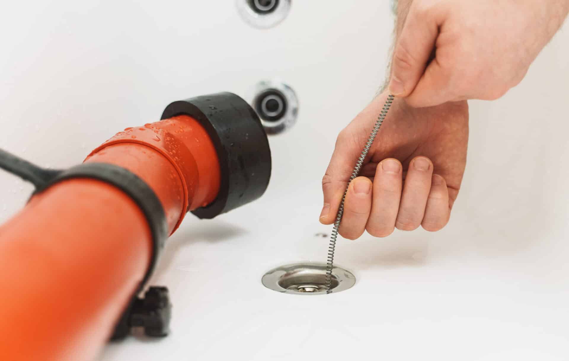 Plumber using a wrench to repair a water pipe under the sink