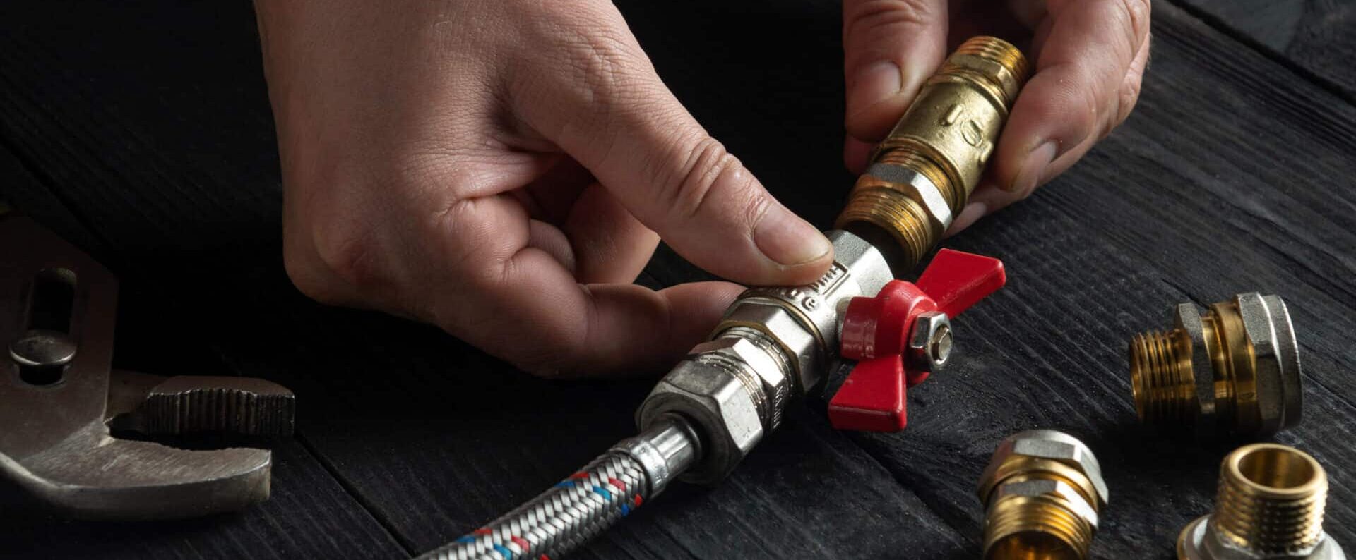 Plumber using a wrench to repair a water pipe under the sink
