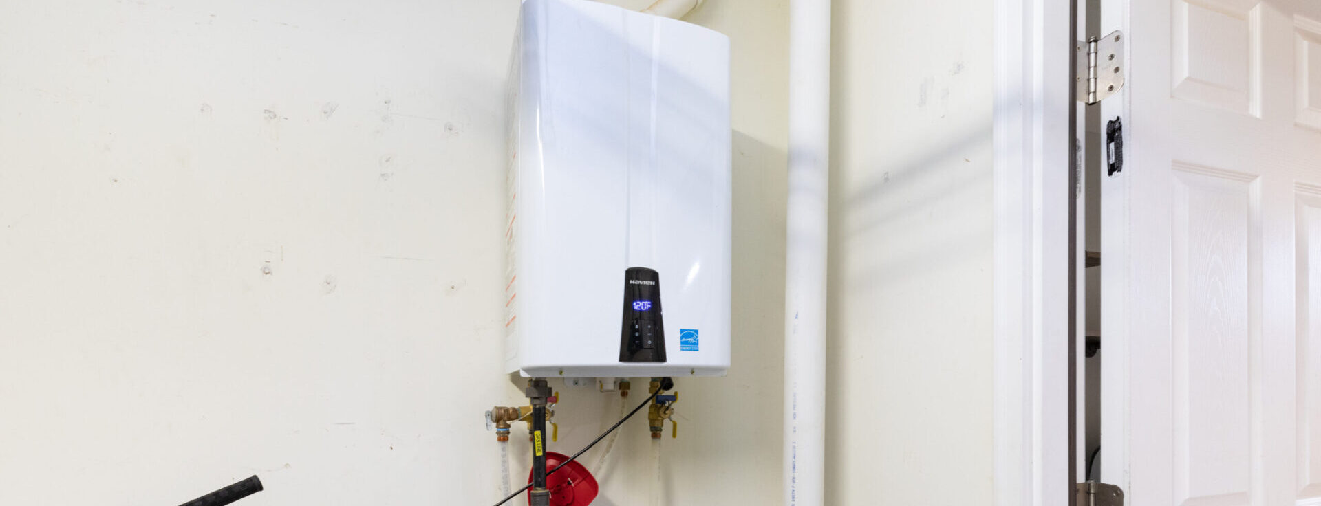 Tankless water heater mounted on a wall, displaying a temperature reading of 120°F on its digital control panel.